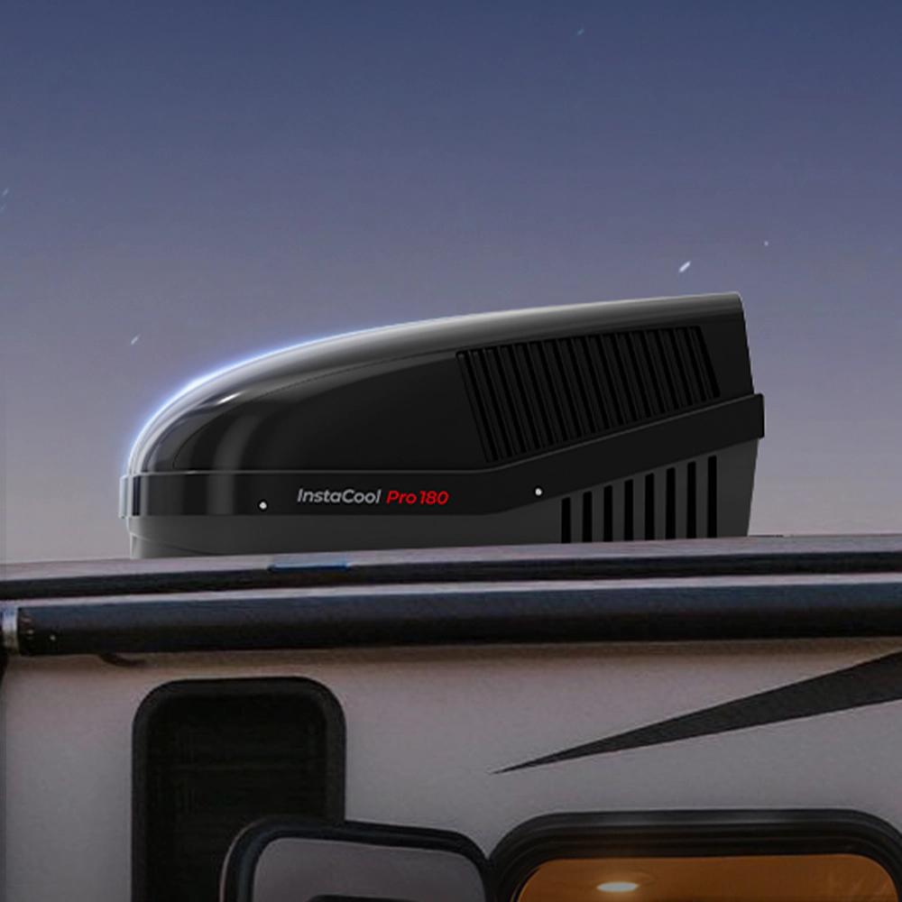 A camper featuring a black roof and a black fogatti air conditioning unit positioned on top, surrounded by open space.