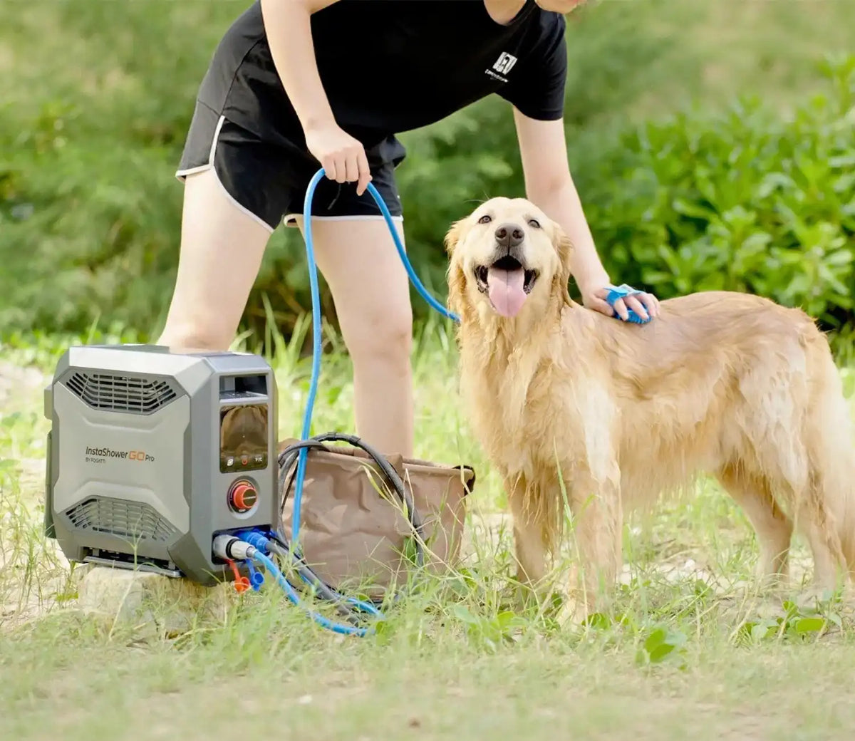 A woman gently pets a dog while holding a portable water heater in her other hand.