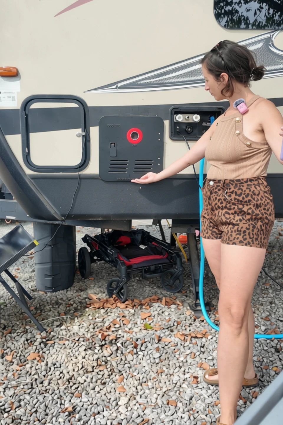 Trisha standing beside her family RV and showing the installed black Fogatti tankless water heater.